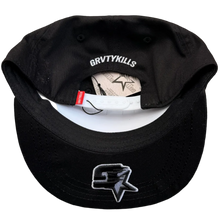 Load image into Gallery viewer, A black baseball cap with a white visor underside, featuring a white 'BRVTYKILLS' text print on the inside and a black-and-white graphic logo on the front, laid flat on a textured gray carpet.
