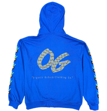 Load image into Gallery viewer, A bright blue hoodie laid flat on a textured carpet, showing the back with a large decorative 'OG' graphic and the text 'Organic Growth Clothing Co.' Below the garment, green shoes are partially visible at the bottom edge.