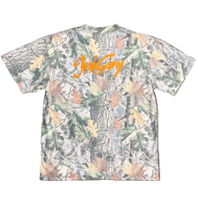 Load image into Gallery viewer, Camouflage-patterned shirt with orange text on a gray surface
