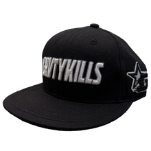 Load image into Gallery viewer, A black flat-brim snapback cap with 'CRITYKILLS' embroidered in white across the front panels and a white star logo on the side, resting on a textured carpet in a room with clothing racks in the background.
