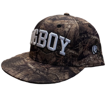 Load image into Gallery viewer, A camouflage baseball cap with 'BIGBOY' embroidered in white on the front, resting on a carpeted floor in a retail store.
