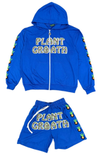Load image into Gallery viewer, A bright blue zip-up hoodie and matching shorts laid flat on a carpeted floor. The hoodie has 'PLANT GROATH' printed across the chest in a white and green pattern, with colorful pineapple graphics down both sleeves.
