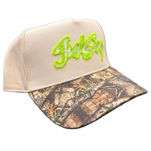 Load image into Gallery viewer, Beige cap with green logo and camouflage bill on a black background
